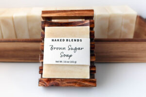 Brown Sugar Soap bar with label, resting on Wooden Soap Dish with other bars behind it.