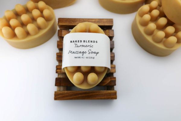 Turmeric Massage Bar Soap with nub design, one labeled and resting on a soap dish, others unwrapped