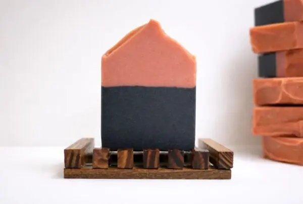 Black Cherry Lemonade Soap bar on a wooden soap dish with layers of pink kaolin clay and charcoal