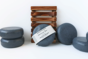 The Working Bar Soap with the label and other soaps around it with a Wooden Soap Dish