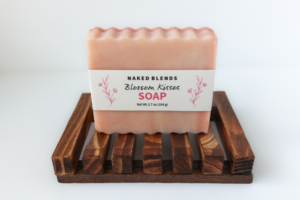 Blossom Kisses Soap bar made with pink rose clay, pictured with a wooden soap dish
