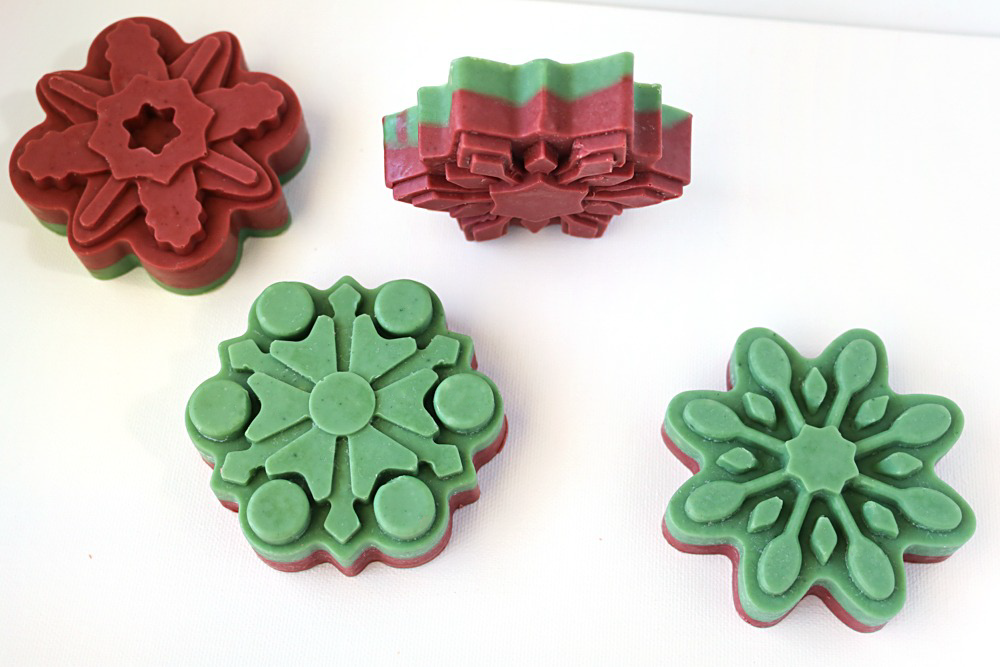 Red and green layered snowflake soaps, including one turned on its side showing the red and green layers, in red-topped and green-topped designs